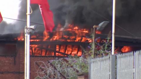 Flames are seen rising out of the rooftop of a red bricked building.