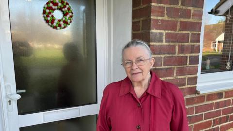 Ann MacLeod stands outside her white front door with a letterbox on Huggens College, Northfleet