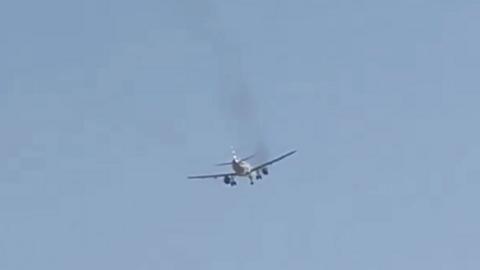 A plane is seen with smoke coming from its engine.
