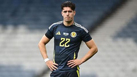 Max Johnston stands pensively with his hands on hips during a break in play during Scotland's friendly against Iceland in June 