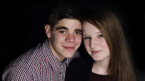 Aaron wearing a checkered shirt and Alex with red hair and black top