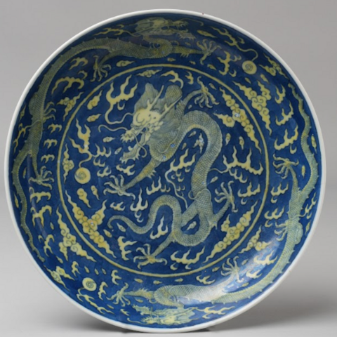 A blue and yellow porcelain dish with a pattern of dragons and other floral-like patterns.
