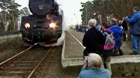 Train enthusiasts watching a steam train arrive at a platform in Poland.