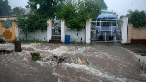 Floodwater rages through street with buildings in the background