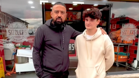 Arfan and Tyler stand together outside Sizzlers. Arfan has his arm around Tyler. Tyler has short brown hair and and Arfan is wearing a black top.