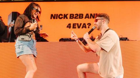 a man down on one knee proposing to his girlfriend on stage