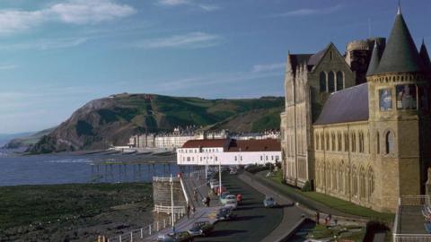 A general view of Old College, a tall brick building overlooking a bay.