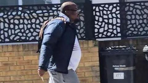 Essa Suleiman, clutching a knife, and weaering a back pack, puffer jacket and white tshirt