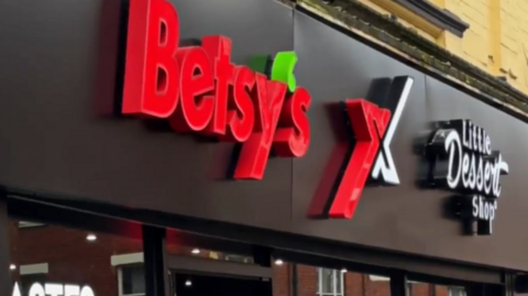 A black and red shop sign saying Betsy's and Little Dessert Shop