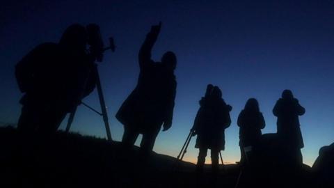 A group of astronomers, silhouetted looking at sky in the Dark Skies Reserve of Bannau Brycheiniog in south Wales