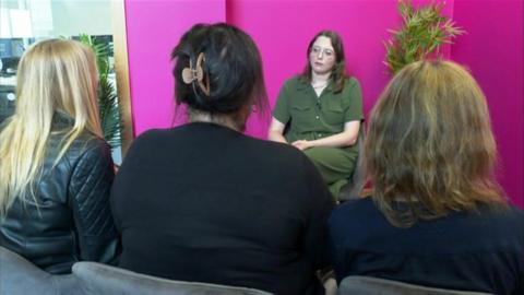 Three women, whose identities are protected, sitting in front of a 鶹ҳ reporter and a pink screen with their backs to the camera