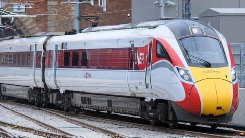 An LNER train emerging from a tunnel on a railway track