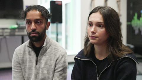 Bipin Khanal, in a grey top and with dark hair and beard, sits beside Leonita Metaj, who has long dark hair, in a youth centre.   