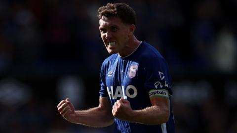 Dara O'Shea celebrates with clenched fists wearing a blue Ipswich Town kit