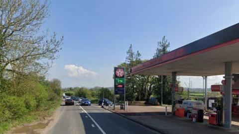 Cars travelling up and down the B4215 near a Texaco petrol station on a sunny day