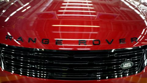 Close-up of the front of a red Range Rover, with the logo in black letters across the bonnet and a Land Rover badge on the radiator grille.
