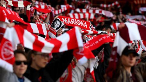 Arsenal fans hold red and white scarves