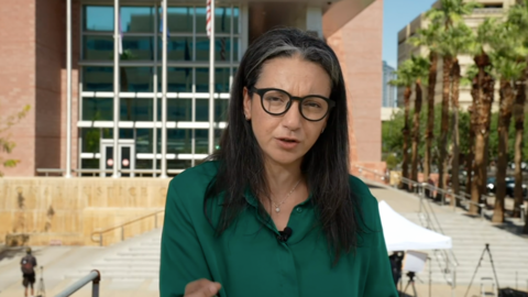 A woman in glasses and a green shirt stands in front of a court house in Las Vegas.