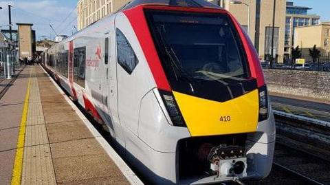 A Greater Anglia train stopped next to a platform. It has a red and yellow face and has Greater Anglia printed on the side.