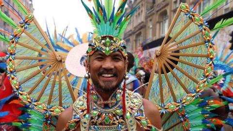 man at the carnival dressed up in green and blue feathers