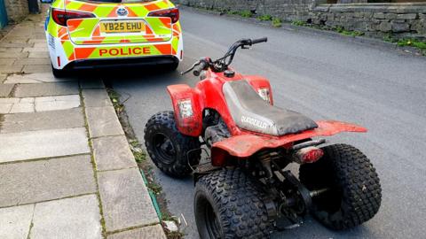 A red quad park parked behind a police car 