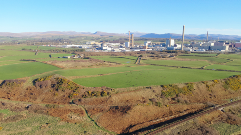 A general view of the land at Moorside next to Sellafield. The aerial image shows a railway line in the foreground, and the Sellafield site in the background, with some green fields in between.