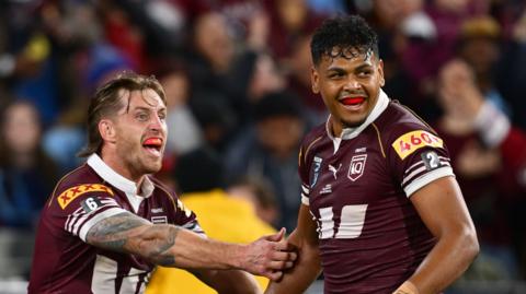 Cameron Munster and Selwyn Cobbo, both grinning with mouthguards showing, celebrate a try