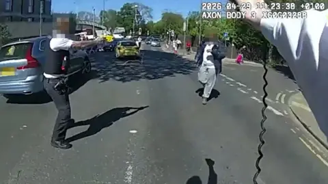 Body-worn footage showing a police officer's arm holding a Taser, another officer to the left and the knife suspect walking towards them