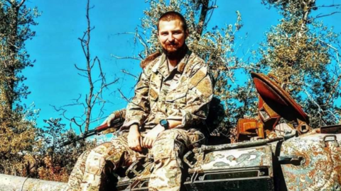 Liam love in combat uniform, sat on a tank in Ukraine