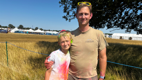 A father and son smiling and hugging in a field on a sunny day