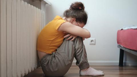 Sad lonely teen sitting on floor near smartphone and crying, feeling depressed. 