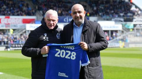 Steve Evans and Chairman Hussain AlSaeed hold a Bristol Rovers shirt between them with 2028 printed on the back