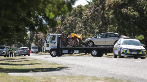 The bike and a silver car are loaded onto the bed of a tow truck