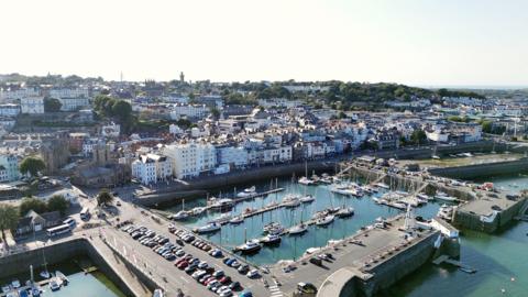 A picture of an image taken from above looking over St Peter Port. There is a number of properties and boats pictured.