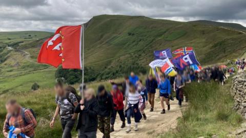 A screengrab from our undercover reporter's footage of a Patriotic Alternative hike on their summer camp in Derbyshire showing members and supporters waving flags