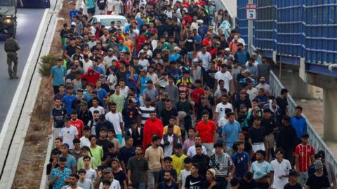Police officers and Spanish soldiers escort a big group of migrants to the border to take them out of Spain, after mass crossings of migrants on foot and by sea from Morocco into Spanish territory, in Ceuta, August 1