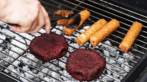 Sausages and burgers cooking on a barbecue.