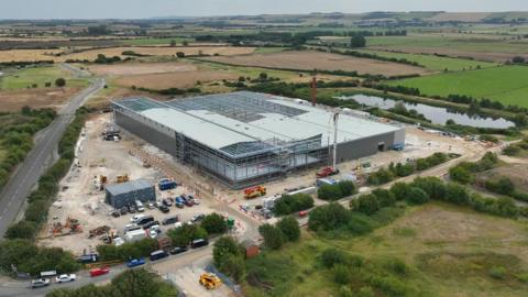 A drone image of the construction of the new manufacturing plant which shows a large square building surrounded by a car park