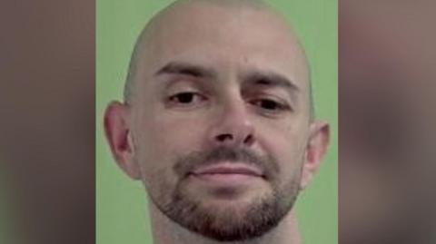 A mugshot of Jamie Smith, a bald man with brown stubble.