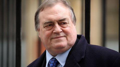 John Prescott pictured in 2012 in London wearing a dark jacket, blue shirt and patterned tie