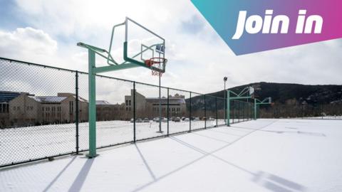 An outside basketball court is covered in snow 