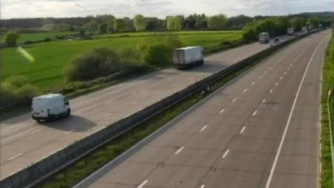 A road with vehicles queuing on one side. The other side of the road has no vehicles on it.