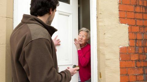 A salesman trying to sell to older woman 