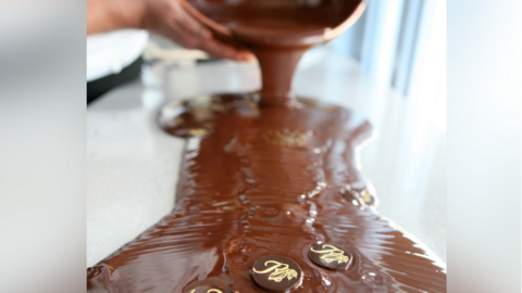 Chocolate being poured on a surface, with Rumsey's branded chocolates getting caught in the flow.
