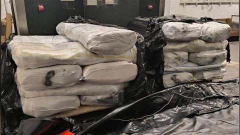 About 15 large packages wrapped in a white material.