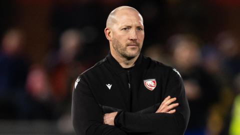 George Skivington stands with his arms folded across his chest