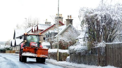 A snow plough drives through snow in Carrbridge in the Scottish Highlands on 19 November 2025.