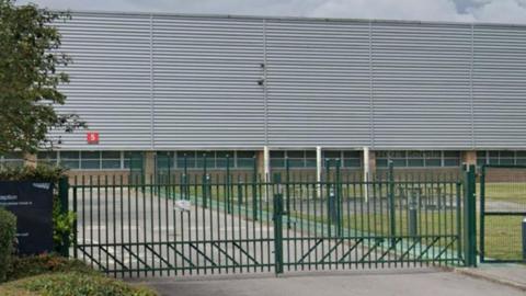 A large building behind green gates.