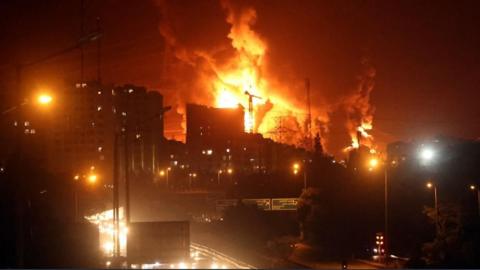 People drive as fire and smoke rise from Tehran's oil warehouse on 15 June 2025 as Israel continues air strikes