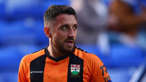Anthony Hartigan head and shoulders shot looking to his left wearing Barnet's orange and black kit